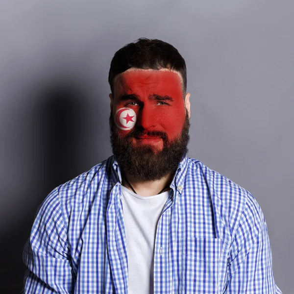 Young man with Tunis flag painted on his face