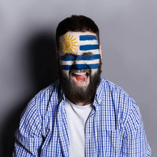 Молодой человек с уругвайским флагом на лице — стоковое фото