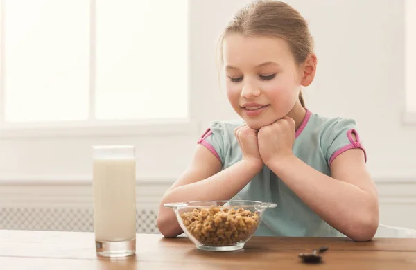 Счастливая девочка смотрит на зернышки и молоко — стоковое фото
