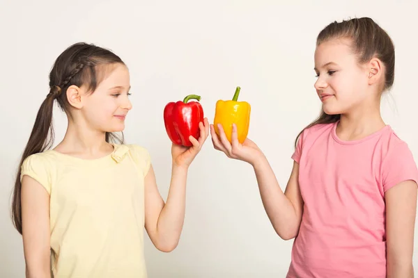 Happy little girls with bell peppers over white background — Stock Photo, Image