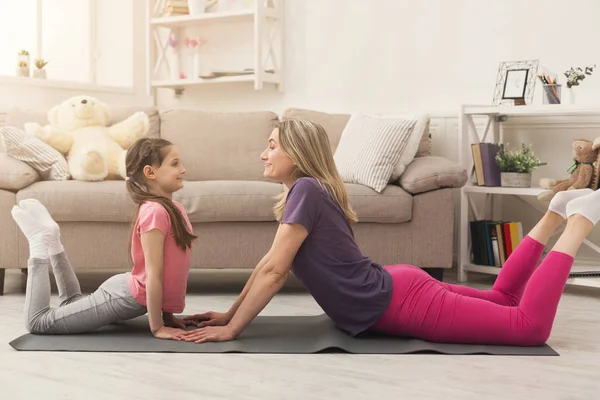 Young woman and child daughter doing yoga exercise at home — Stock Photo, Image