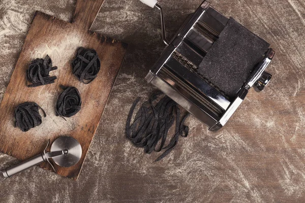 Nido de tagliatelle negro crudo en la mesa de la cocina — Foto de Stock