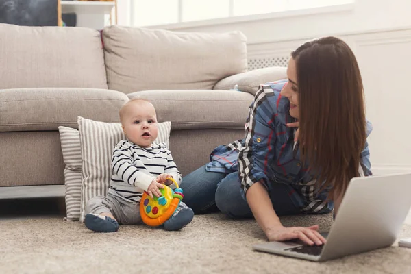 Jeune mère qui travaille et passe du temps avec bébé — Photo