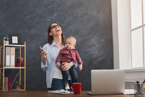 Ung mamma innehav baby medan du talar i telefon — Stockfoto