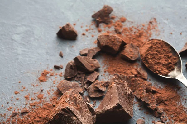 Krossad choklad bitar och kakao på grå bakgrund — Stockfoto