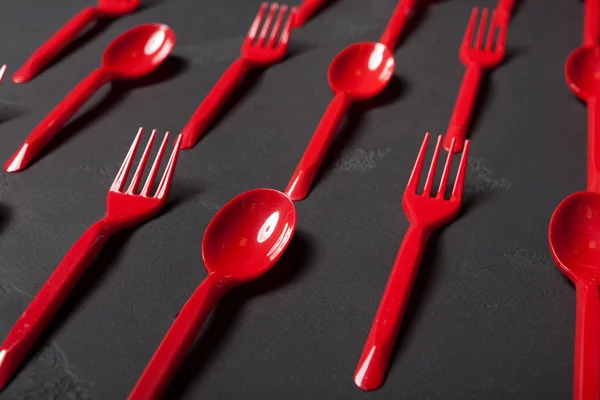 Vista dall'alto su forchette e cucchiai di plastica su sfondo nero — Foto Stock