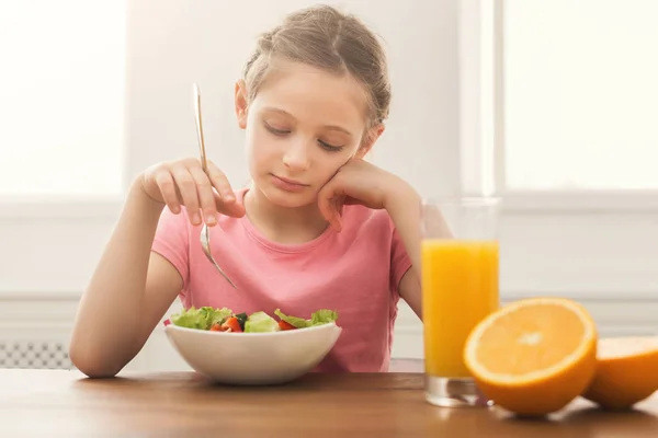 Сумна дівчинка їсть свіжий салат і п'є апельсиновий сік — стокове фото