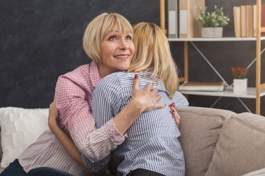 Mutlu yetişkin anne ve kızı evde kucaklayan