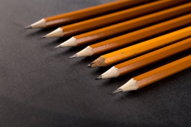 One old and plenty of new pencils on black background clipart