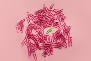 Unique green paperclip with plenty of pink ones clipart