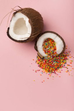 İçinde şeker sprinkles, pembe bir arka plan ile Hindistan cevizi yarıya indirir