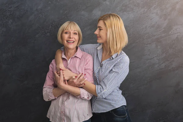 Madre e hija adultas abrazándose sobre fondo gris —  Fotos de Stock