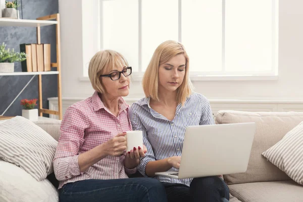 Adult mor och dotter använder laptop hemma. — Stockfoto