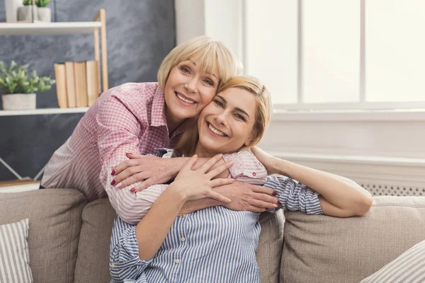 Adult mor och dotter embracing hemma — Stockfoto