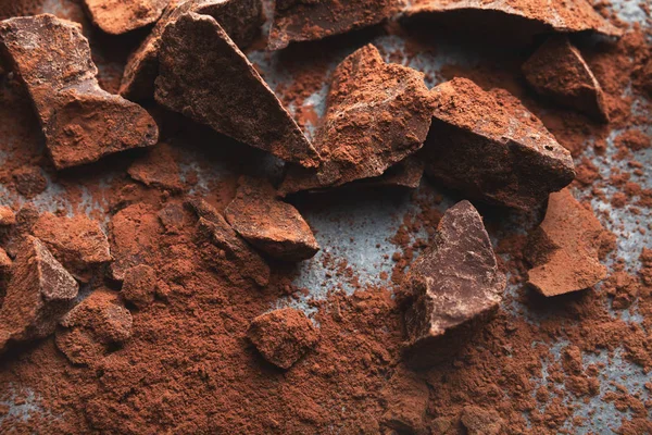 Piezas de chocolate trituradas y cacao sobre fondo gris —  Fotos de Stock