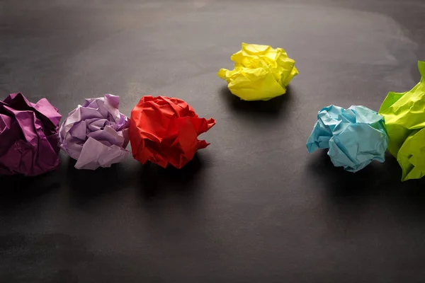 Bolas de papel multicolores arrugadas sobre fondo negro — Foto de Stock