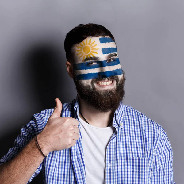 Junger Mann mit uruguayischer Flagge im Gesicht — Stockfoto