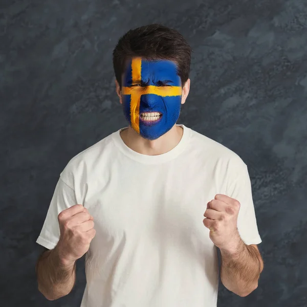 Młody człowiek z flaga Szwecji malowane na twarzy — Zdjęcie stockowe
