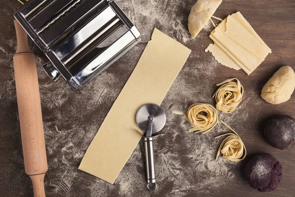 Nido de tagliatelle crudo y masa en la mesa de cocina — Foto de Stock