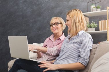 Mutlu yetişkin anne ve kızı dizüstü evde kullanma.