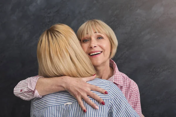 Feliz madre adulta e hija abrazando sobre fondo gris — Foto de Stock