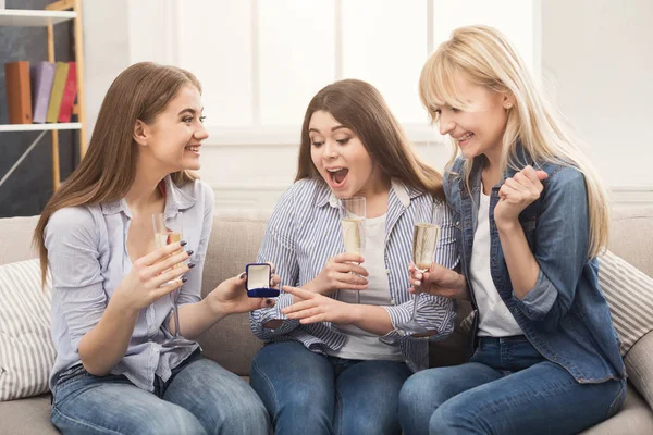 Young happy girl showing her proposal ring to surprised girlfriends