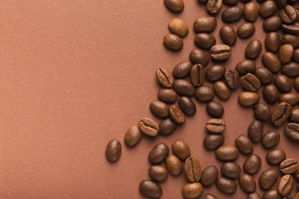 Heap of brown coffee beans on pink background — Stock Photo, Image