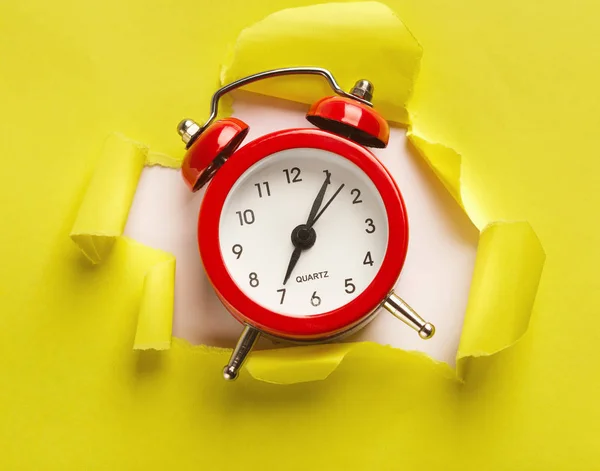 Reloj despertador en fondo de papel amarillo desgarrado — Foto de Stock