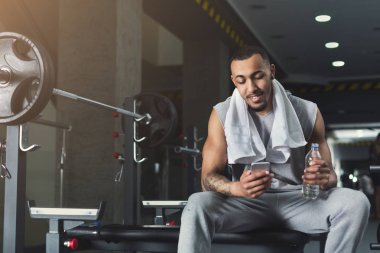 Spor salonunda cep telefonuyla siyah vücut geliştirmeci