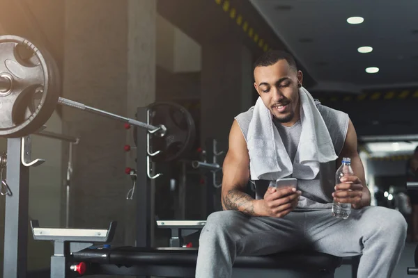 Culturista negro usando teléfono móvil en el gimnasio —  Fotos de Stock