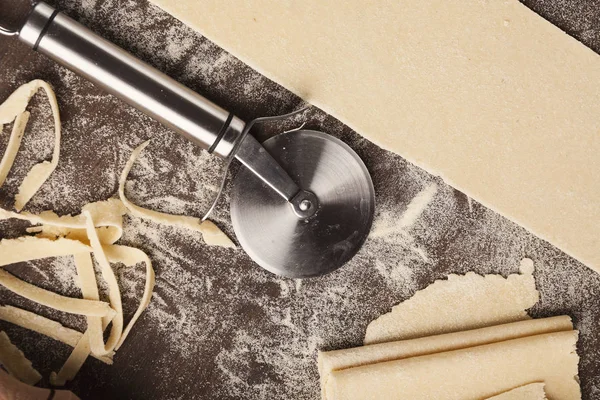 Сире тісто і колісний різак на кухонному столі — стокове фото