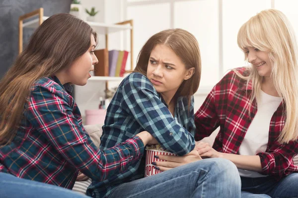 Serious young women do not sharing popcorn with friend