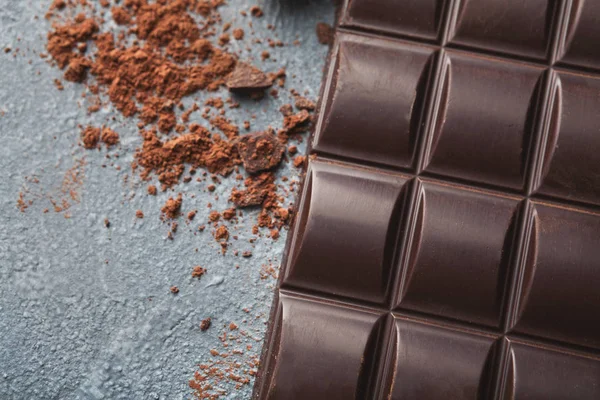 Crushed chocolate bar pieces and cocoa on gray background — Stock Photo, Image