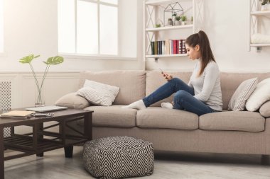 Kanepenin üzerinde cep telefonu kullanan genç kız