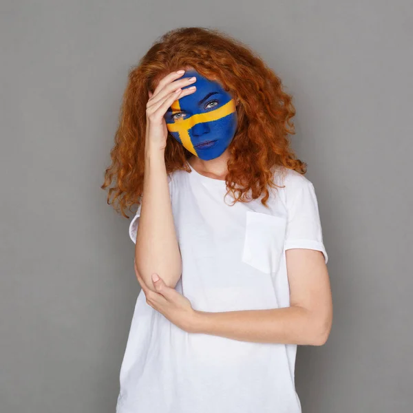 Jovem mulher com bandeira da Suécia pintada em seu rosto — Fotografia de Stock