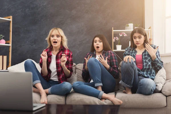 Frightened young women watching movie at home
