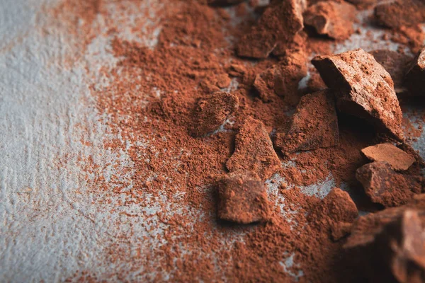 Piezas de chocolate trituradas y cacao sobre fondo gris — Foto de Stock