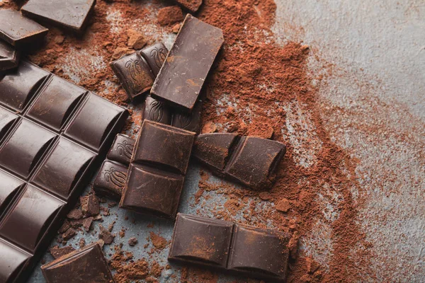 チョコレート ・ バーの部分と灰色の背景にココアを粉砕 — ストック写真