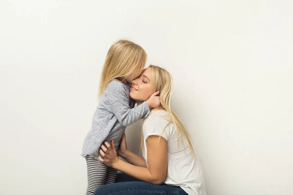 Mãe e filha felizes abraçando no estúdio — Fotografia de Stock