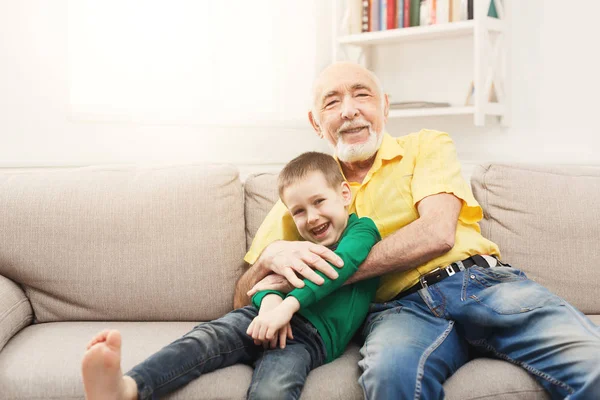 Mały chłopiec siedzi na kanapie z dziadkiem — Zdjęcie stockowe