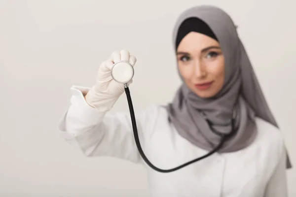 Жінка в хіджабі, що показує стетоскоп на студійному фоні — стокове фото