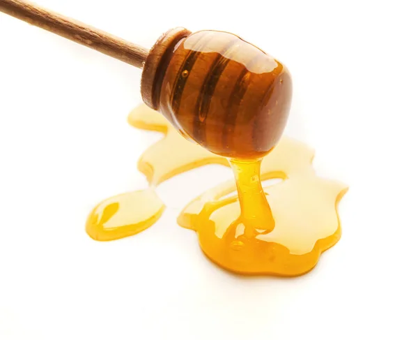 Рідкий мед, що ллється з дерев'яної ложки на білому ізольованому фоні — стокове фото