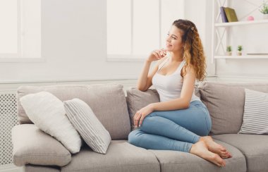 Bej kanepe üzerinde düşünme genç Kızıl saçlı kadın