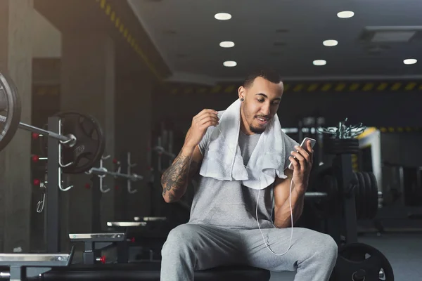 Sportsman in headphones choose music on phone — Stock Photo, Image