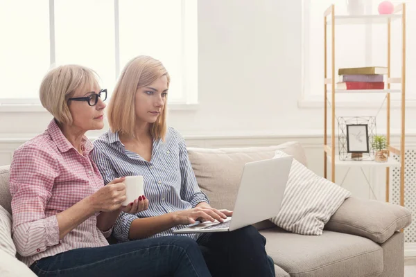 Allvarlig vuxen mor och dotter använder laptop hemma. — Stockfoto