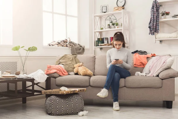 Wanita putus asa duduk di sofa di ruang berantakan — Stok Foto