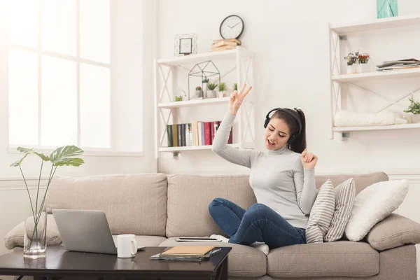 Joyeux jeune femme dans les écouteurs sur canapé beige — Photo