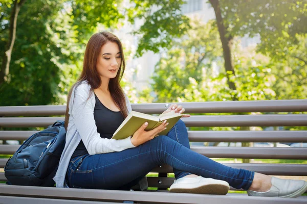 Молода азіатка сидить на лавці в парку. Розслабляючись і читаючи книгу — стокове фото