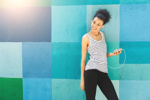 African-american woman posing, leaning on bright wall — Stock Photo, Image