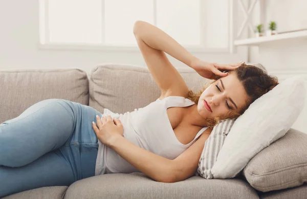 Trauriges rothaariges Mädchen, das Schmerzen auf dem Sofa spürt — Stockfoto